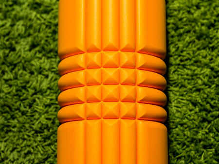 Orange foam roller on green carpet backgroundの写真素材