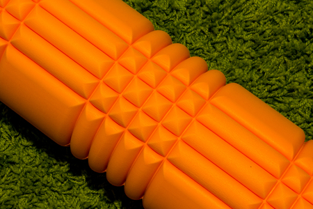 Orange foam roller on green carpet backgroundの写真素材