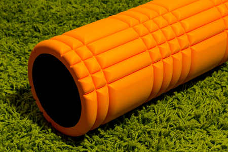 Orange foam roller on green carpet backgroundの写真素材