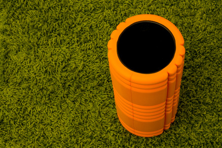 Orange foam roller on green carpet backgroundの写真素材