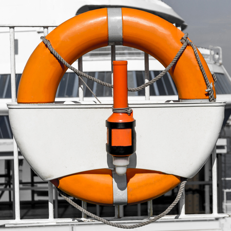 Orange rubber flotation ring on black and white background with shipの写真素材