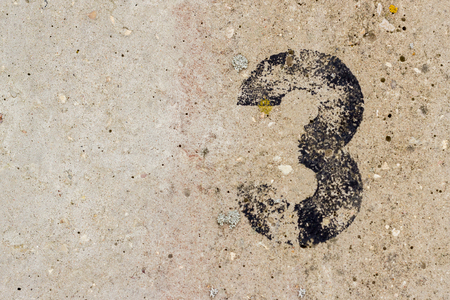 Black number three 3 painted on old rugged light grey concrete wall background with copy spaceの写真素材