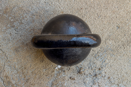 Old rusty black kettlebell 16 kg pood on noncrete floor background top viewの写真素材
