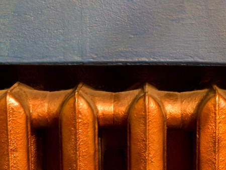Copper heating radiator with blue wall background and copy space closeupの写真素材