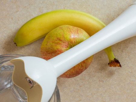 Glass, white blender and fruit, banana and apple prepared for making smoothie, on a kitchen table, view from the topの写真素材