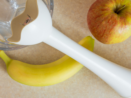 Glass, white blender and fruit, banana and apple prepared for making smoothie, on a kitchen table, view from the topの写真素材