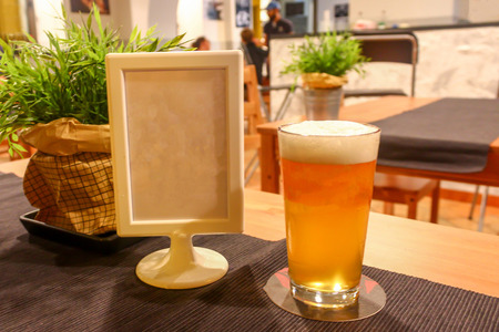 Full glass of light orange juicy tasty beer on a dark grey table in a cozy craft beer bar with copy spaceの写真素材