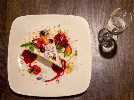 Cheescake with strawberies and a glass of sparkling water on wooden table backgroundの写真素材
