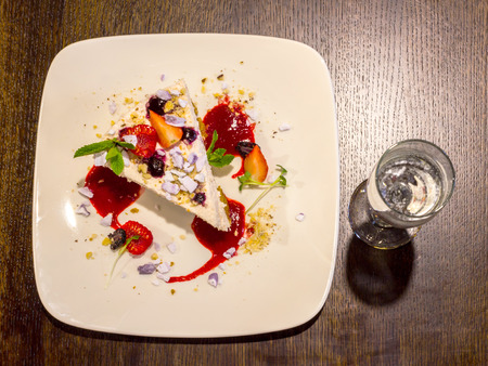 Cheescake with strawberies and a glass of sparkling wine on wooden table backgroundの写真素材