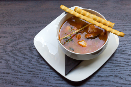 Delicious seafood soup with shrimps, prawns, oysters, mussels and jelly in a white soup plate on black table backgroundの写真素材