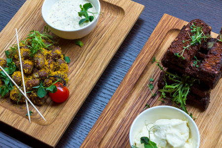 Chicken hear meat snack and roasted garlic bread snack with white sauces on wooden platters on black table background top view closeupの写真素材