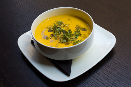 Root vegetable yellow cream soup on black wooden table background angle viewの写真素材