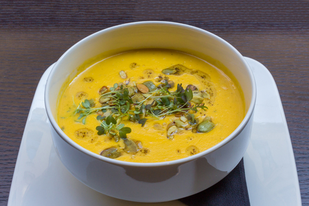 Root vegetable yellow cream soup on black wooden table backgroundの写真素材