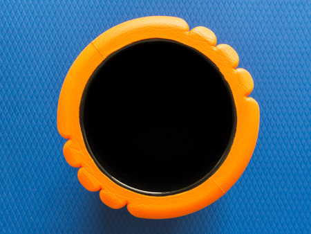 Orange fitness foam roller top view of black hole circle on blue scale texture backgroundの写真素材