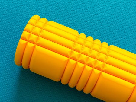 Yellow fitness foam roller on cyan scale texture backgroundの写真素材