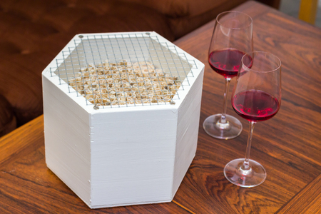 White wooden insect hotel on a table with two red wine glassesの写真素材