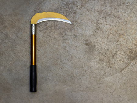 Yellow sickle with black handle on concrete floor with copy spaceの写真素材