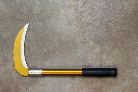Yellow sickle with black handle on concrete floor with copy spaceの写真素材
