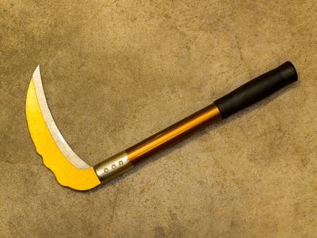 Yellow sickle with black handle on concrete floor with copy spaceの写真素材
