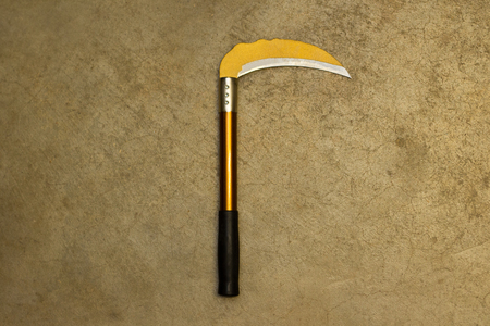 Yellow sickle with black handle on cracked concrete floor with copy spaceの写真素材