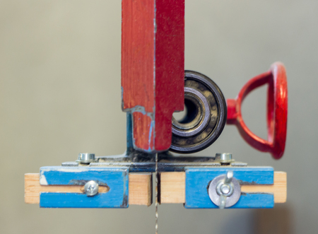 Red and blue machine saw tool mechanism on a work bench with tuning handle in a workshopの写真素材