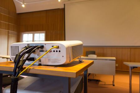 White screen projector in front of a screen in a conference or lecture hall with a white projector screenの写真素材