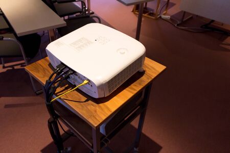 White screen projector  on a wooden stance in a dark conference or lecture hallの写真素材