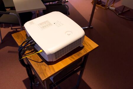 White screen projector  on a wooden stance in a dark conference or lecture hallの写真素材