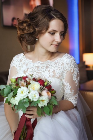 Young and beautiful bride with flower bouquet in hotelの写真素材