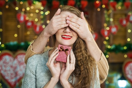 Man surprising his delighted girlfriend with purple square boxの写真素材