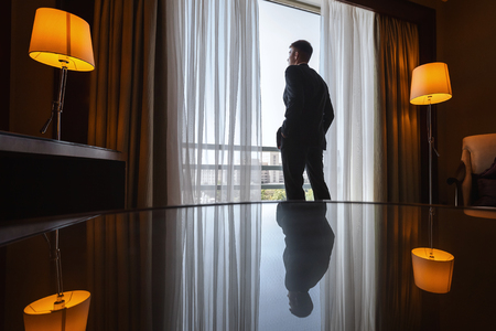 man in suit standing near windowの写真素材