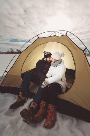 boy and girl in winter clothes sitting in a tentの写真素材
