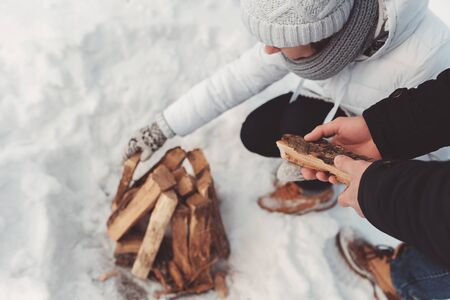 girl and boy put firewood on snowの写真素材