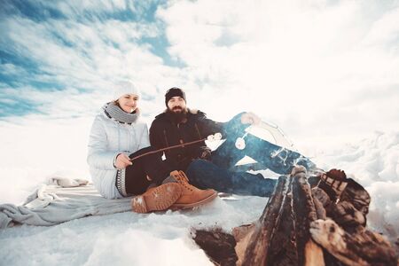 lovers roast marshmallow over a campfireの写真素材
