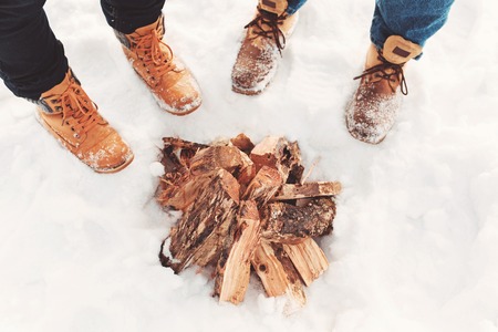 Two people stand in the snow near campfireの写真素材