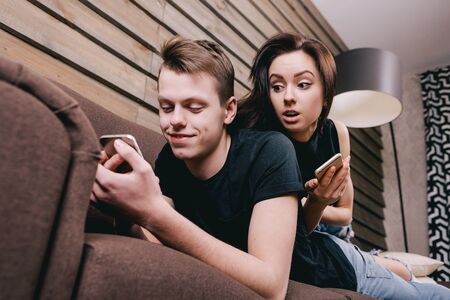 young couple in bed with smartphone in handsの写真素材