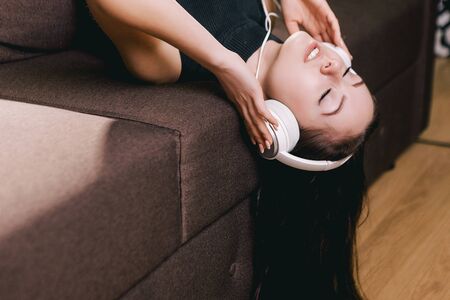 beautiful brunette girl lying in bed, listening music and singing