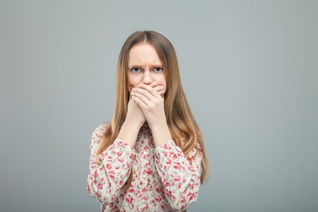 girl covers her mouth with her handsの写真素材