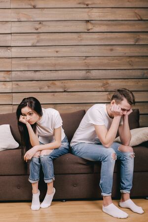 sadness girl and guy sitting on bed at home