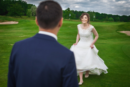 Happy bride running to meet her groom on a meadowの写真素材