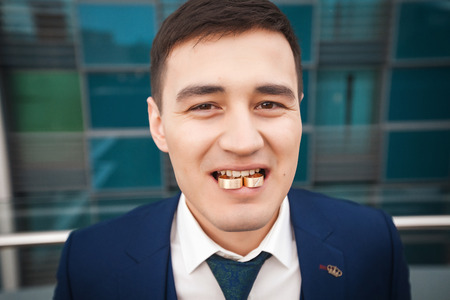 Groom in a suit holding rings in his mouthの写真素材