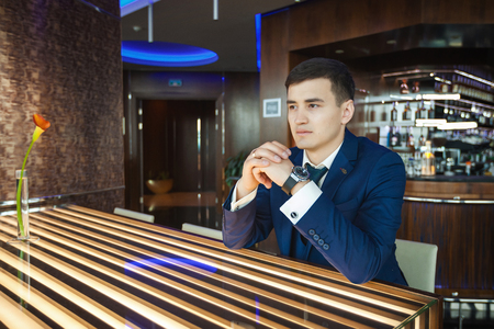 Groom sitting at the table in a bar and waiting for his brideの写真素材