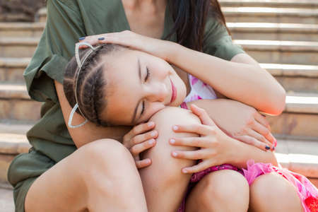 Little girl putting head on mothers kneesの写真素材