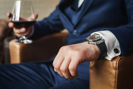 Groom holding glass of whiskey sitting on the chair, close up viewの写真素材