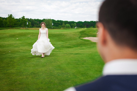 Bride walking to meet her groom on a green meadowの写真素材