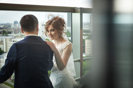 beautiful newlywed couple near window with city landscapeの写真素材