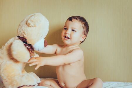 little boy with teddy bear in bedroom. Newborn child smiling and relaxing in bed. Nursery for young children. Family morning at homeの写真素材