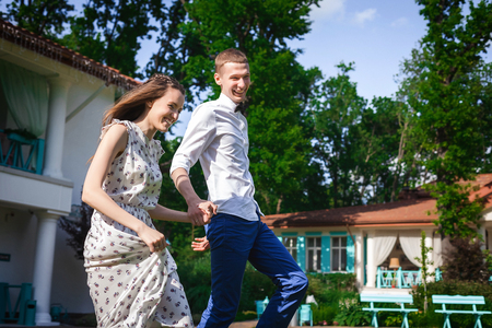 Funny happy romantic lovers walking outdoors. girl dressed in beige dress with pattern. guy wearing white shirt and bow tieの写真素材