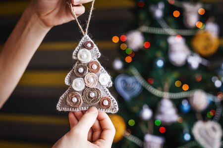 little new year tree in hands background and xmas decorations with toys, sparkling, glowing. Happy New Year and Xmas themeの写真素材