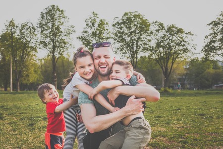 father with three children having fun in the park. hipster style. casual clothes. concept of happy familyの写真素材